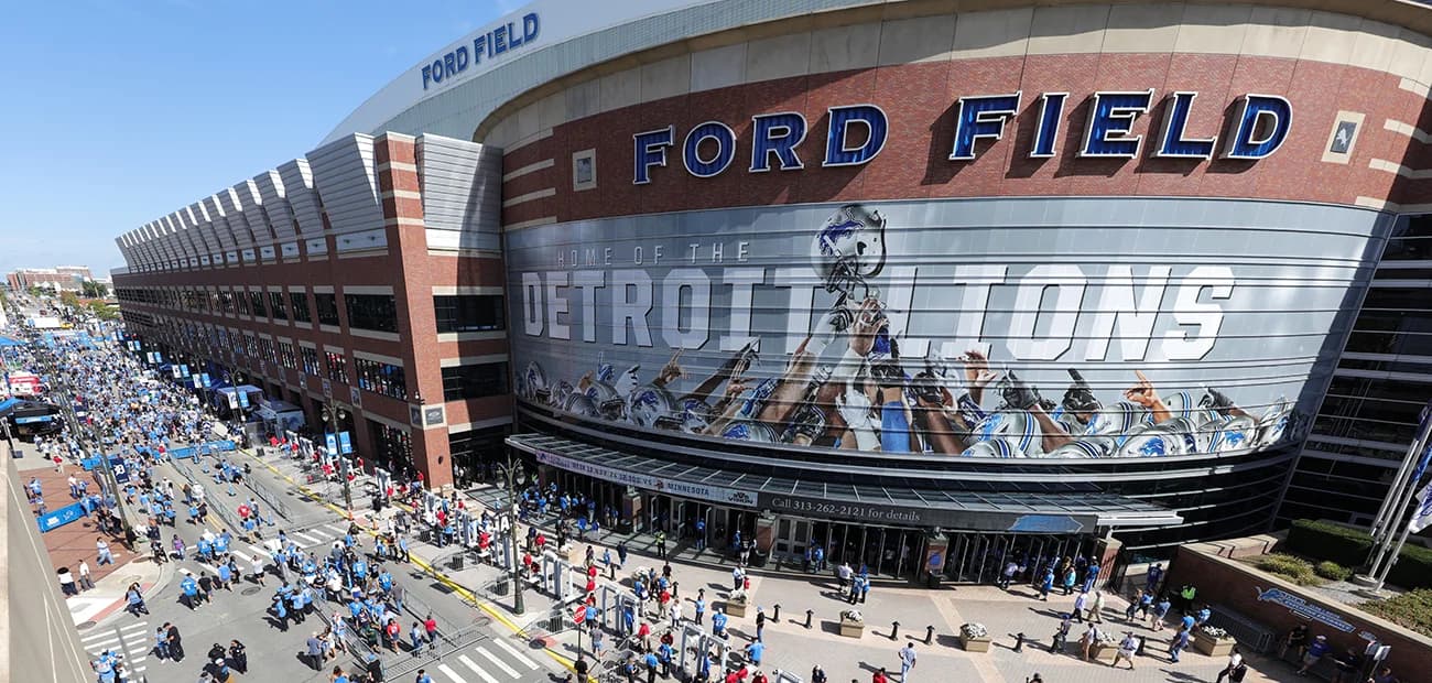 A general view of Ford Field filled with Detroit Lions fans on game day, Honolulu Blue throughout the bowl and the downtown Detroit skyline visible through the window wall