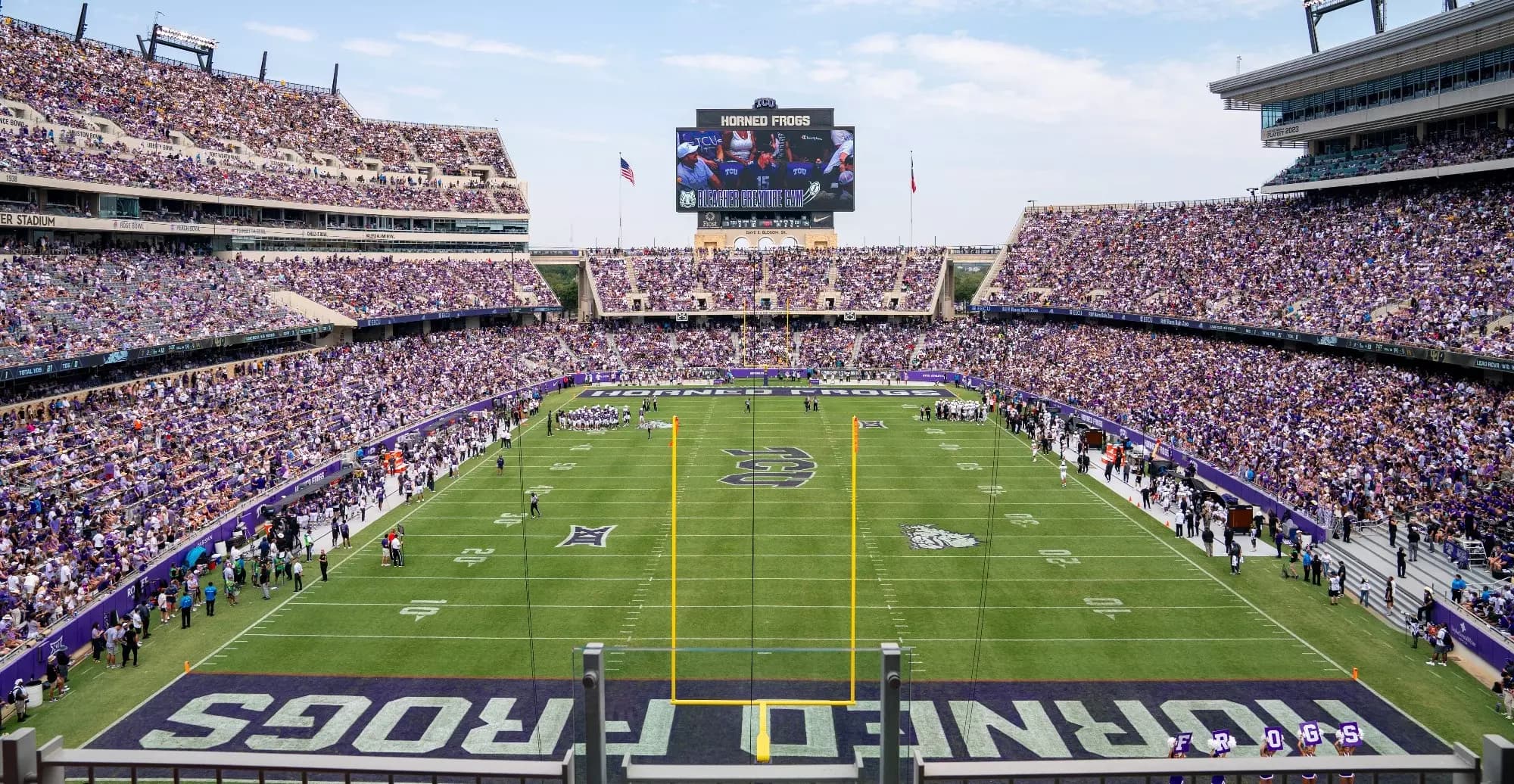 A sold-out Amon G. Carter Stadium washed in purple on a Texas afternoon — HORNED FROGS painted across both end zones, Riff Ram Bah Zoo running the ribbon boards, and the videoboard rising over the north-end arches with the bowl-game roll call ringing the upper deck