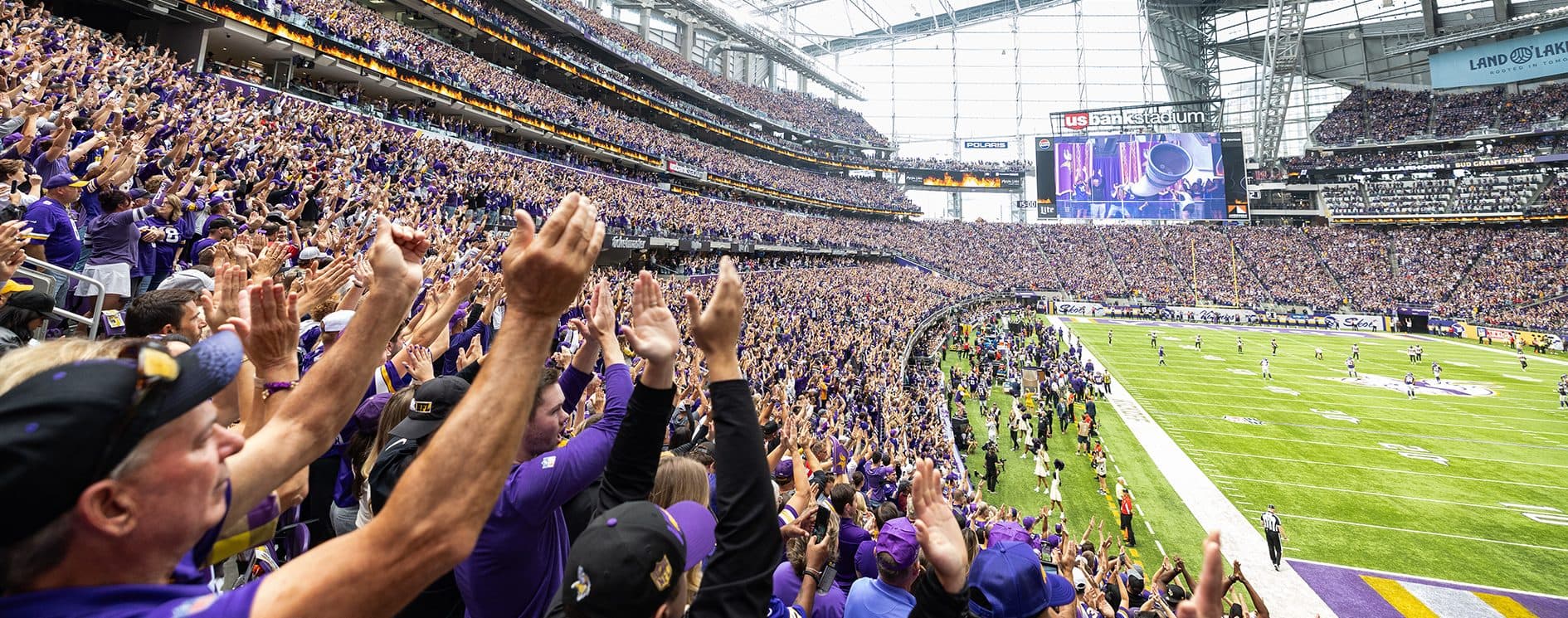 A general view of U.S. Bank Stadium filled with Minnesota Vikings fans on game day, the angular glass roof and downtown Minneapolis skyline visible beyond the bowl