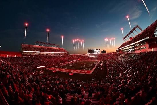 SHI Stadium at night — fireworks climbing over a scarlet crowd as Rutgers takes the field