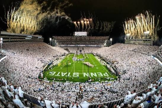 The Beaver Stadium White Out at night — more than 106,000 in white, fireworks ringing the rim, PENN STATE painted below