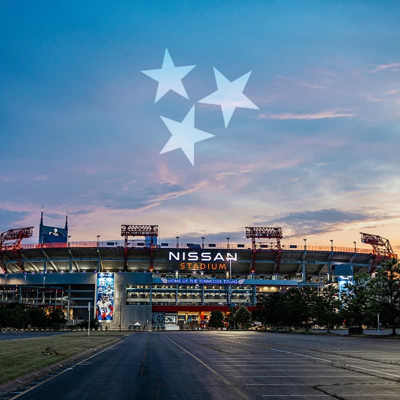 A general view of Nissan Stadium filled with Tennessee Titans fans on game day, two-tone blue throughout the bowl and the downtown Nashville skyline beyond the Cumberland River