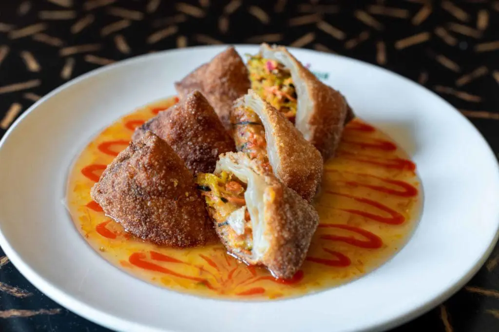Crispy fried spring rolls sliced open over a sriracha-drizzled plate at Amsterdam Café