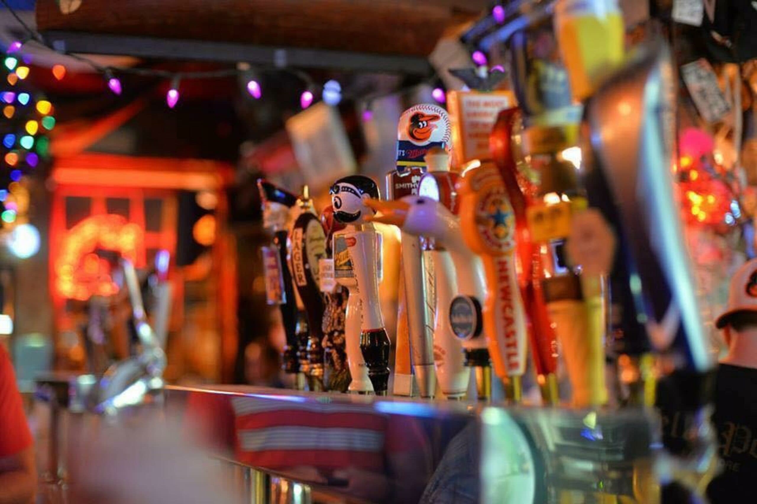 A row of beer tap handles at Cat's Eye Pub, string lights and neon glowing over the bar