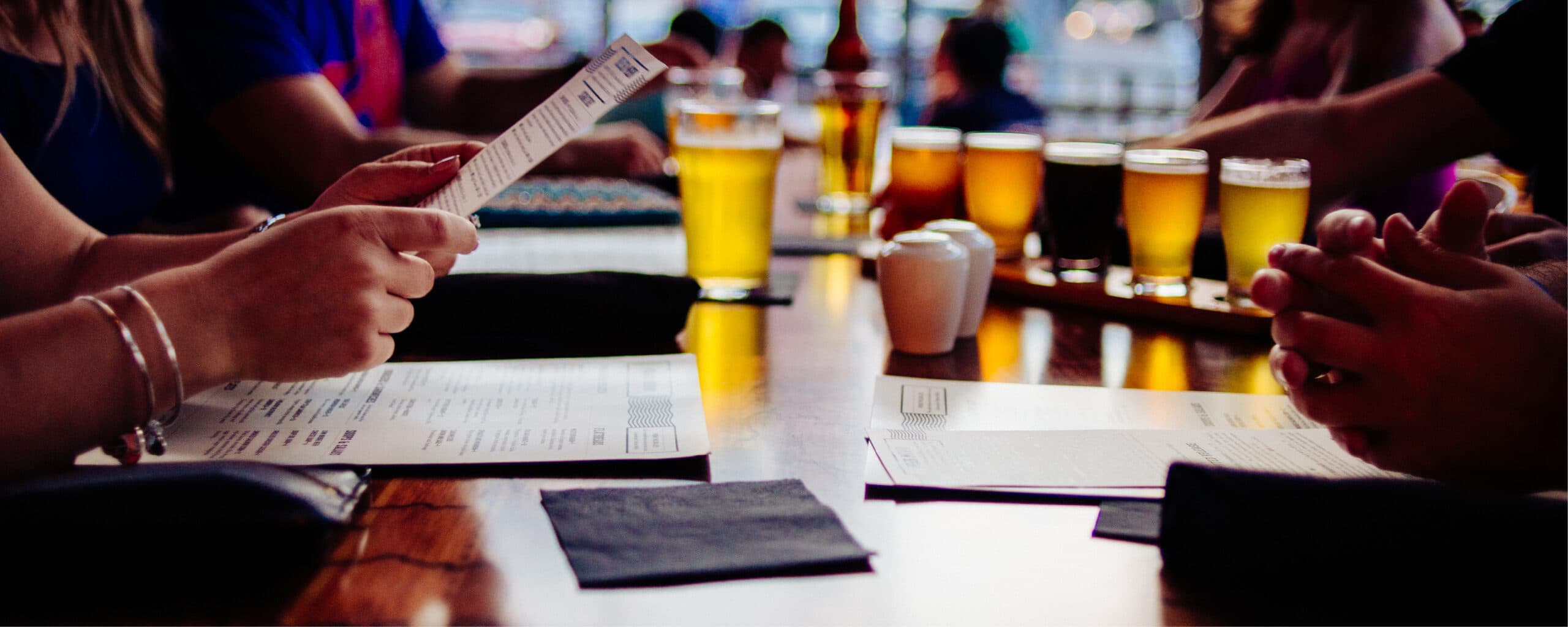 A flight of beers lined up on the bar at Big Ditch Brewing's taproom, menus and coasters in front