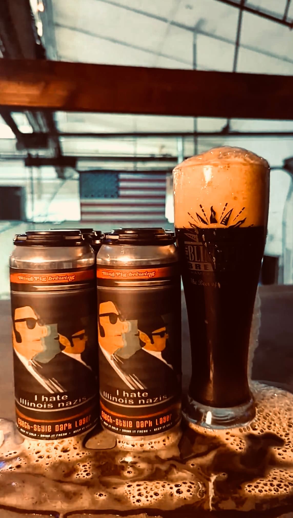 Blind Pig Brewing dark lager cans next to a full branded pint glass on the taproom bar