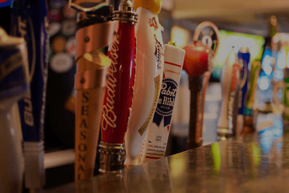 A close-up row of draft beer tap handles along the bar at He's Not Here