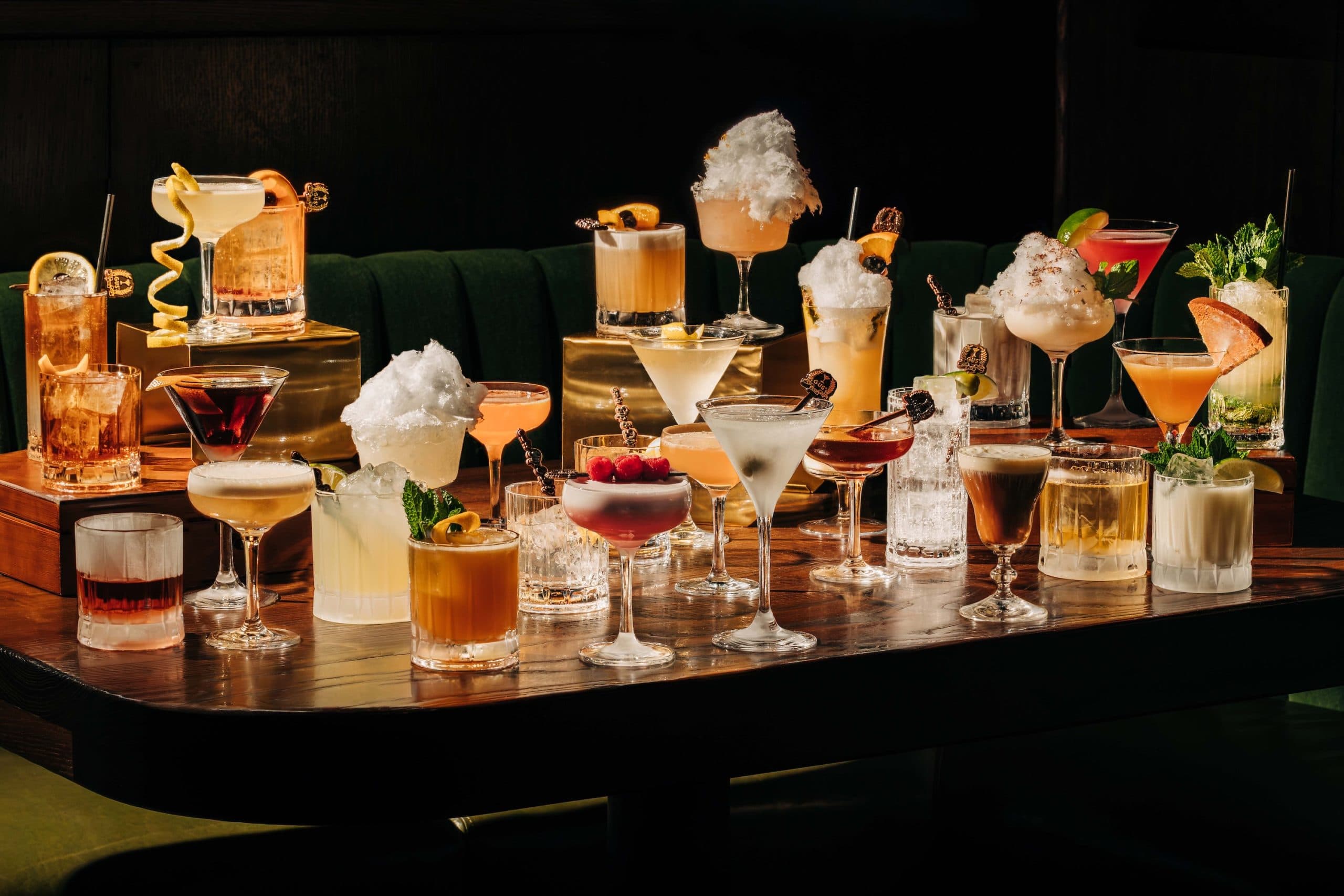 An elaborate spread of craft cocktails, from martinis to cotton-candy-topped drinks, lined up on the bar at Gus' Sip & Dip