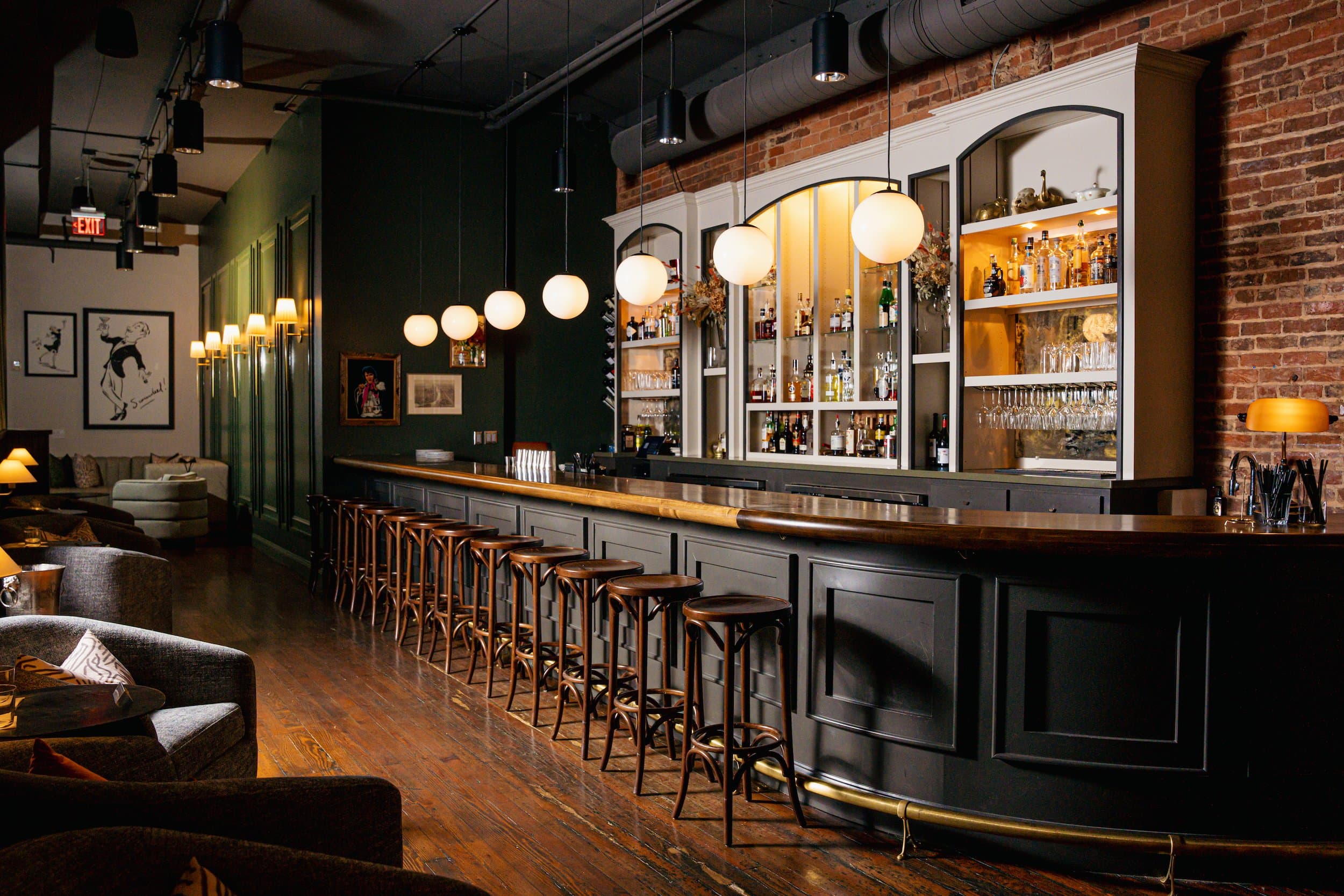 Scoundrel's curved bar interior with globe pendant lights, exposed brick, and a framed \