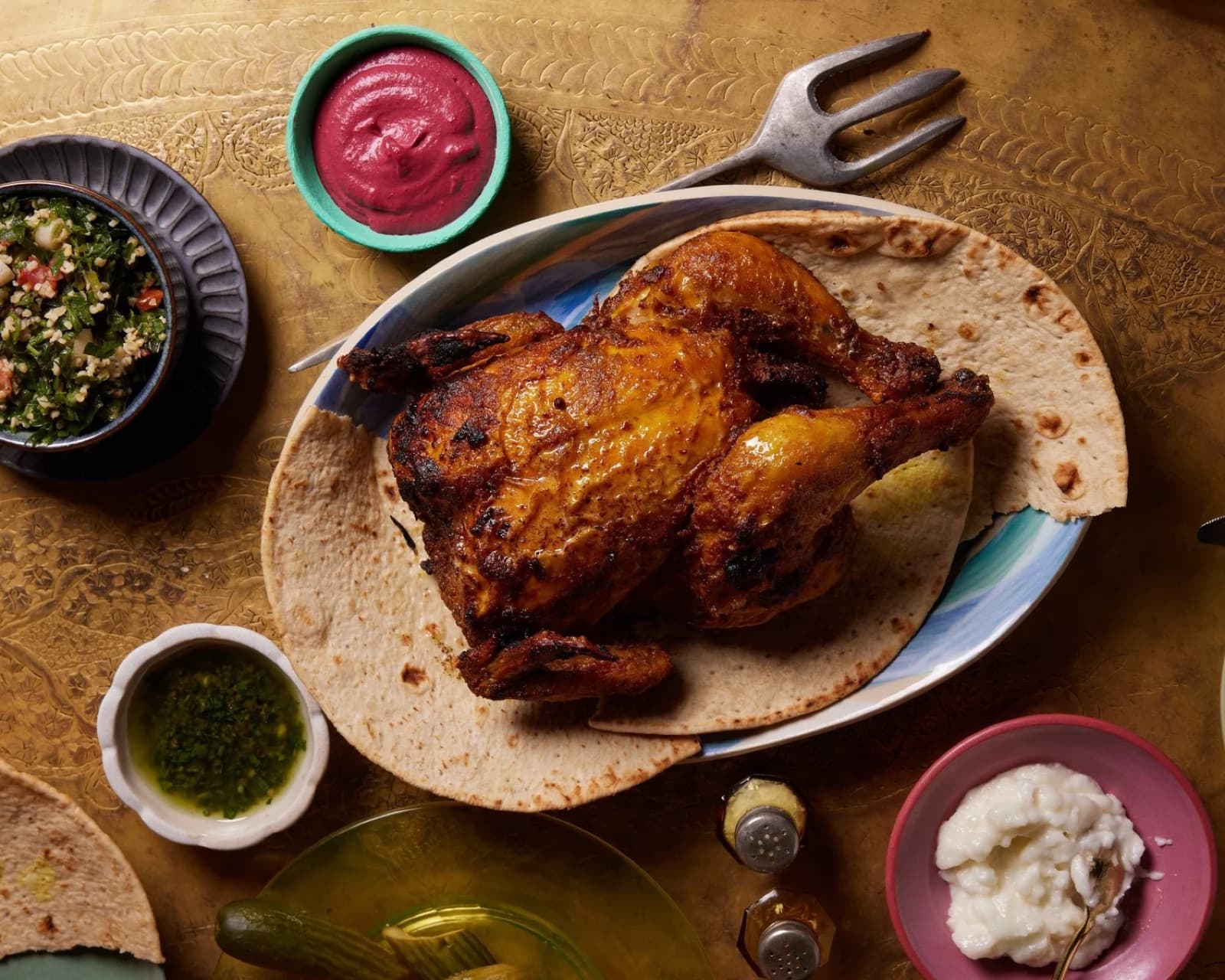 A whole roasted chicken on flatbread at Maydan, served with tabbouleh, harissa, and toum