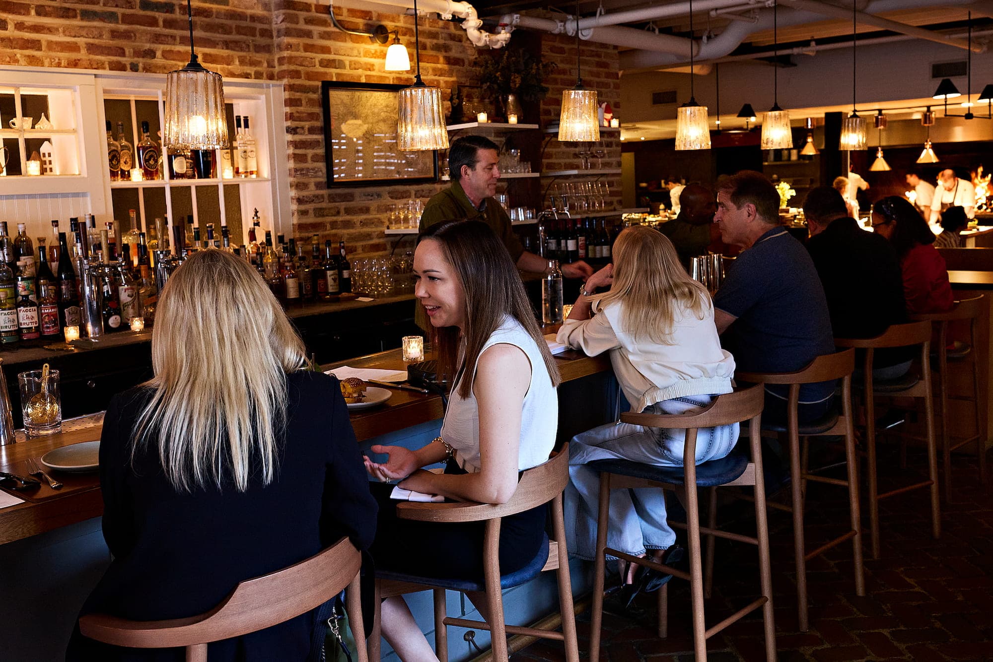 The exposed-brick bar at The Dabney with a bartender pouring drinks and guests seated along the counter
