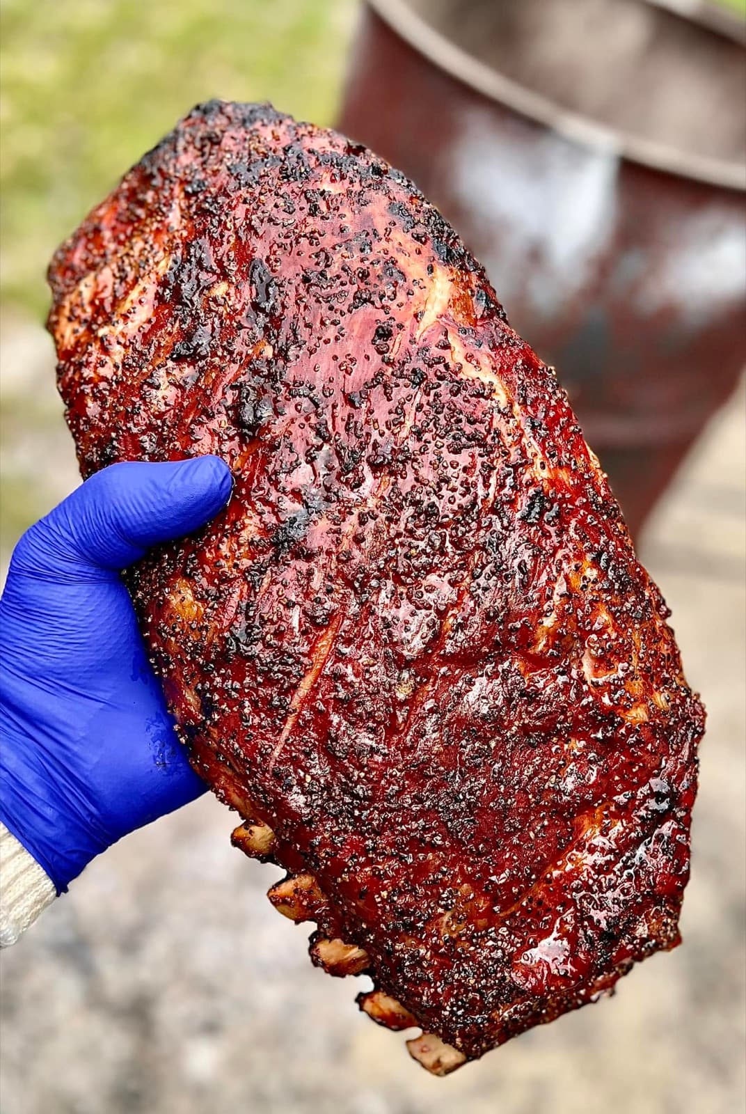 A hand holding up a smoked rack of ribs at City Limits Barbeque