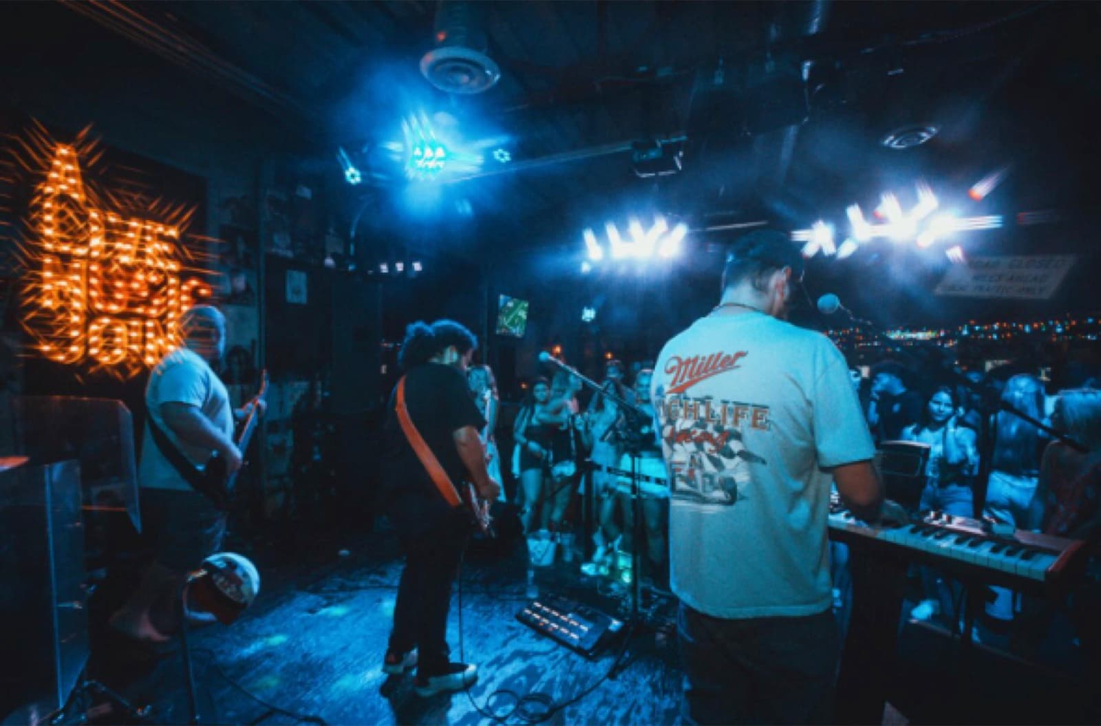 A band performing under a 'World Famous Tin Roof' sign, string lights strung across the bar