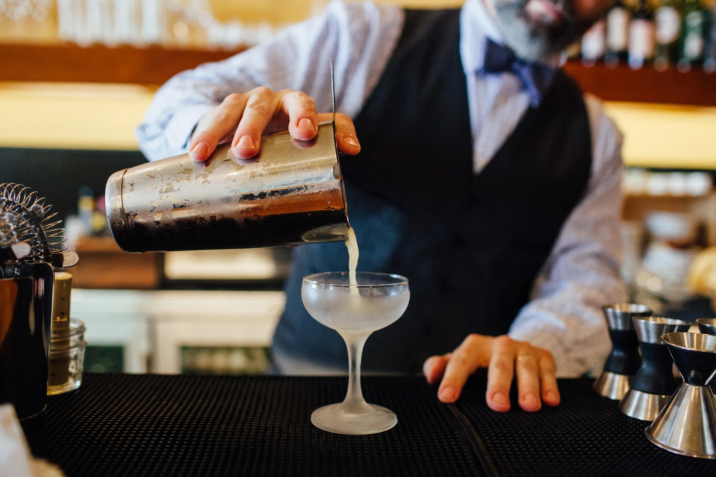 A bartender garnishing a cocktail with a lime wheel at Alley Twenty Six, four finished drinks lined up on the bar