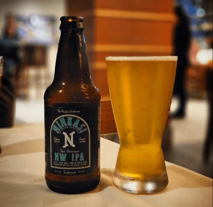 A bottle and freshly poured glass of Ninkasi Total Domination NW IPA on a bar table