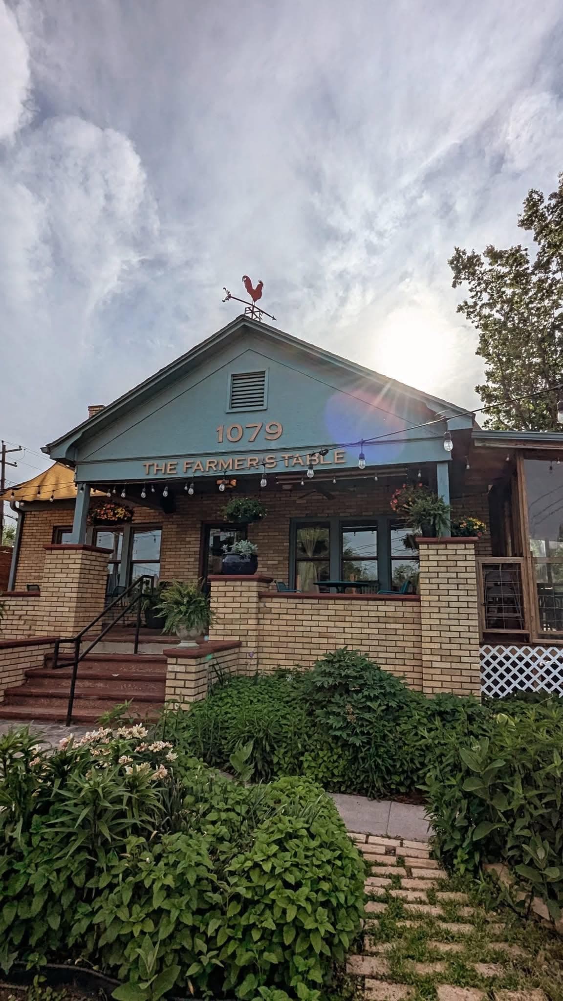 The Farmer's Table Cafe's teal bungalow exterior with '1079 The Farmer's Table' lettering on the porch