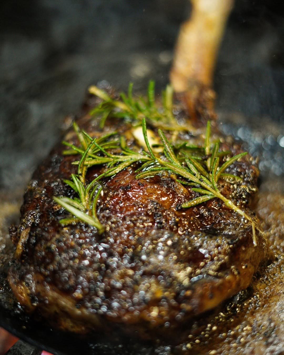 A rosemary-topped bone-in ribeye seared in a cast iron skillet at Lonesome Dove Western Bistro
