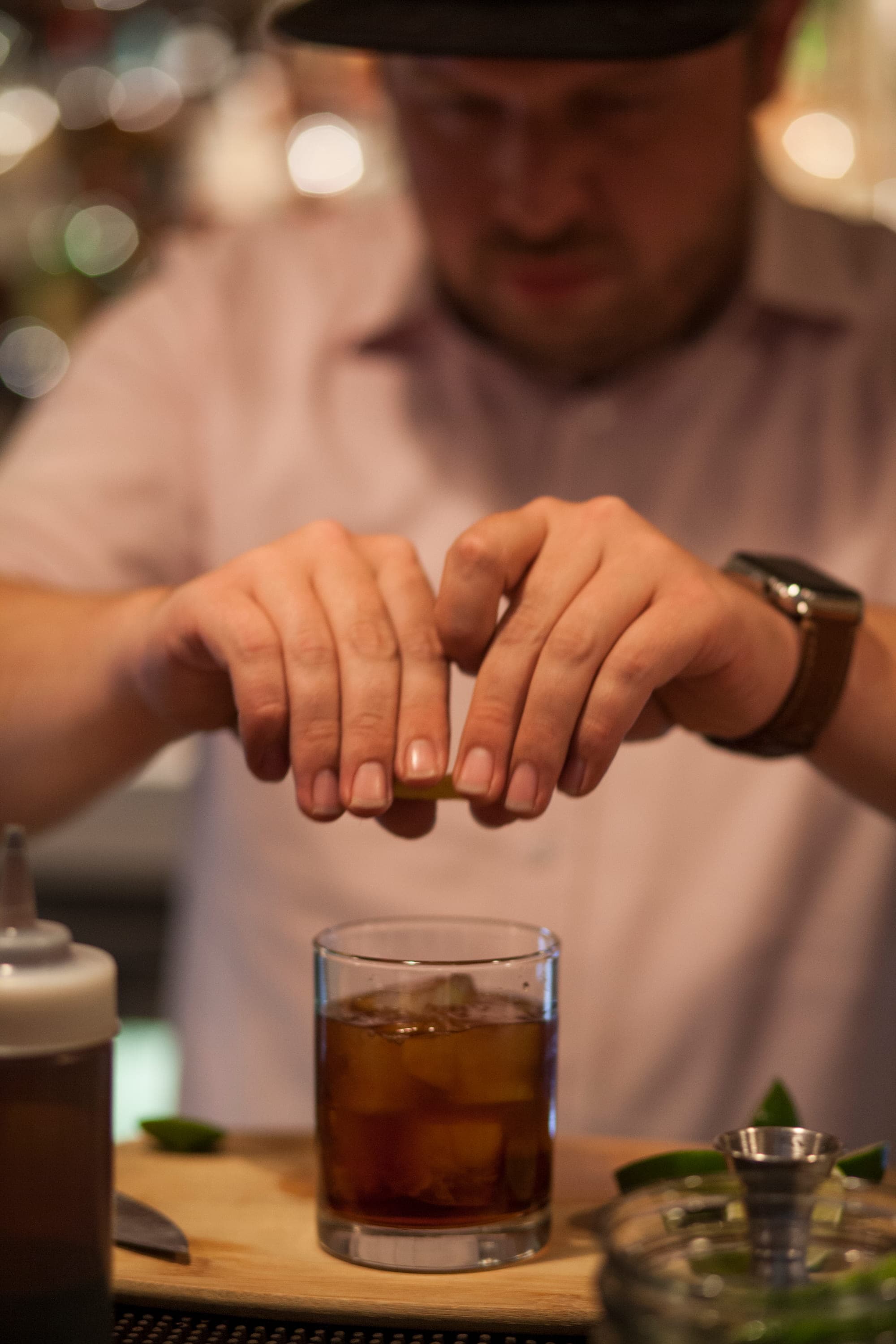 A bartender at The Usual expressing a citrus twist over an old fashioned on the bar