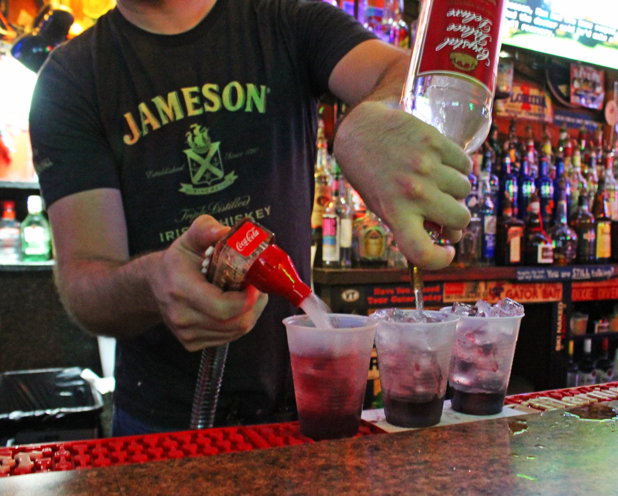 A bartender pouring drinks behind the crowded, neon-lit bar at Salty Dog Saloon