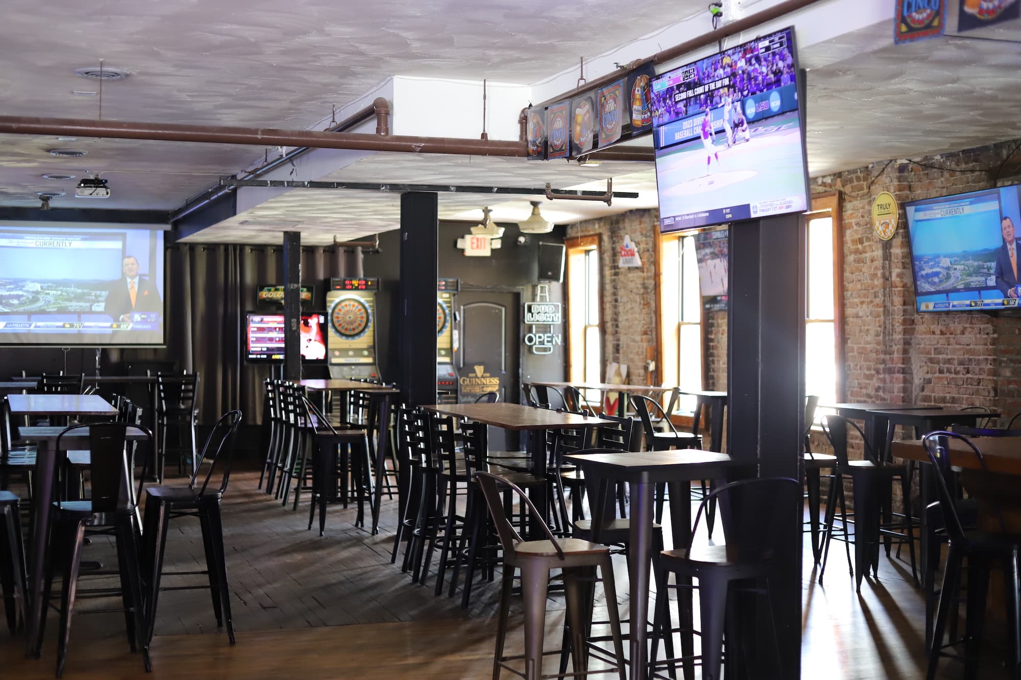 Old City Sports Bar's exposed-brick main room with pub tables and multiple TVs tuned to games
