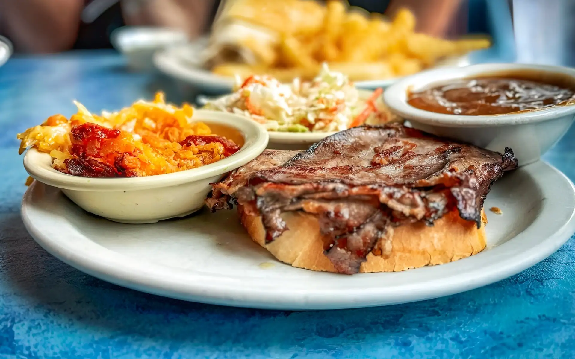 A chopped-beef sandwich plate at Pete's Coffee Shop with mac and cheese, coleslaw, and a cup of gravy