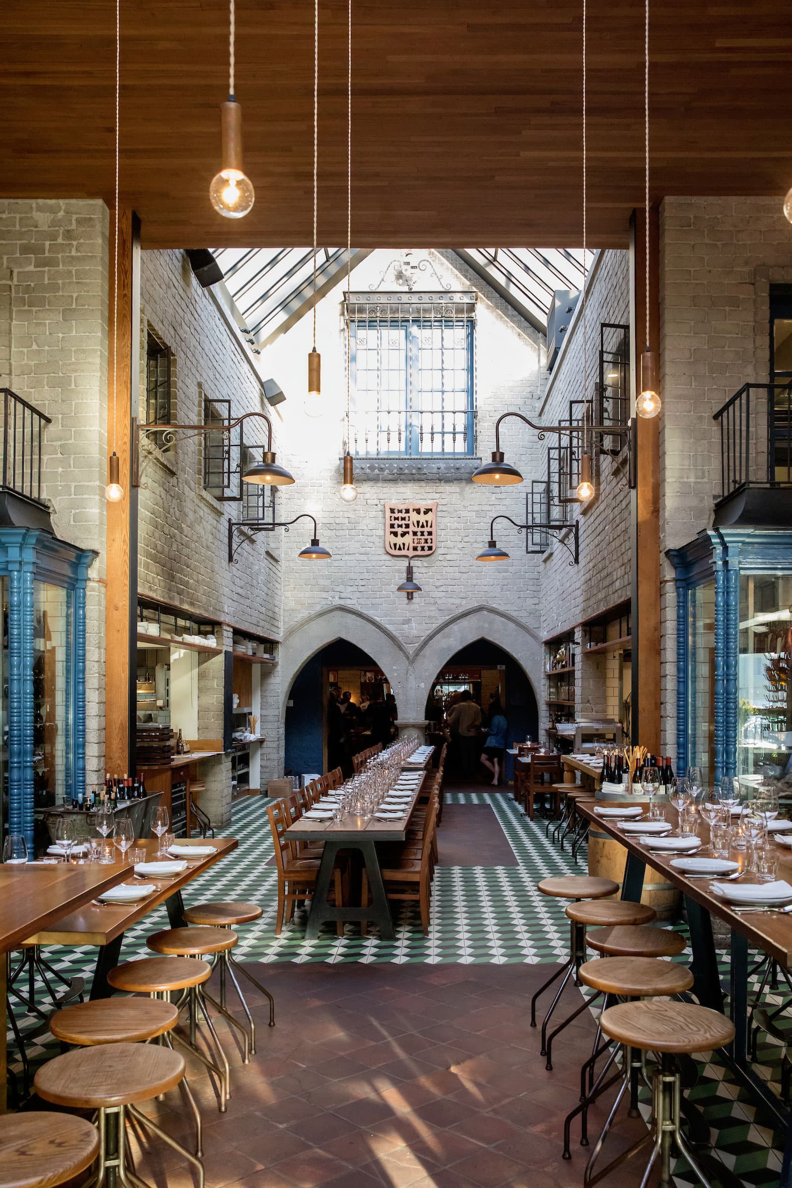 République's soaring vaulted dining room with arched brick doorways, skylight, and long communal tables set for service