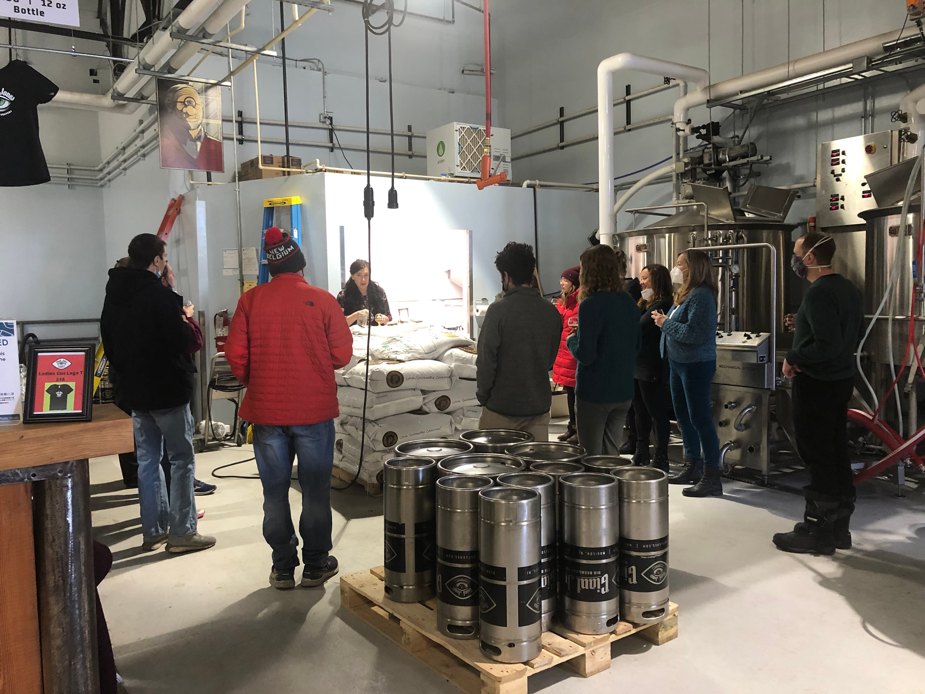 A group tour inside the Giant Jones taproom, with branded kegs stacked in front of the brew tanks