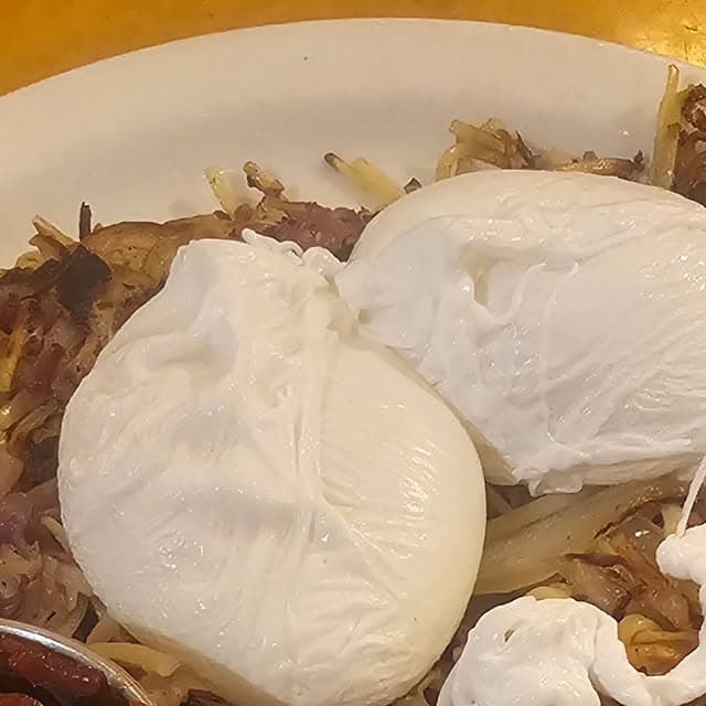 Two poached eggs over hashbrowns and corned beef on a plate at Al's Breakfast