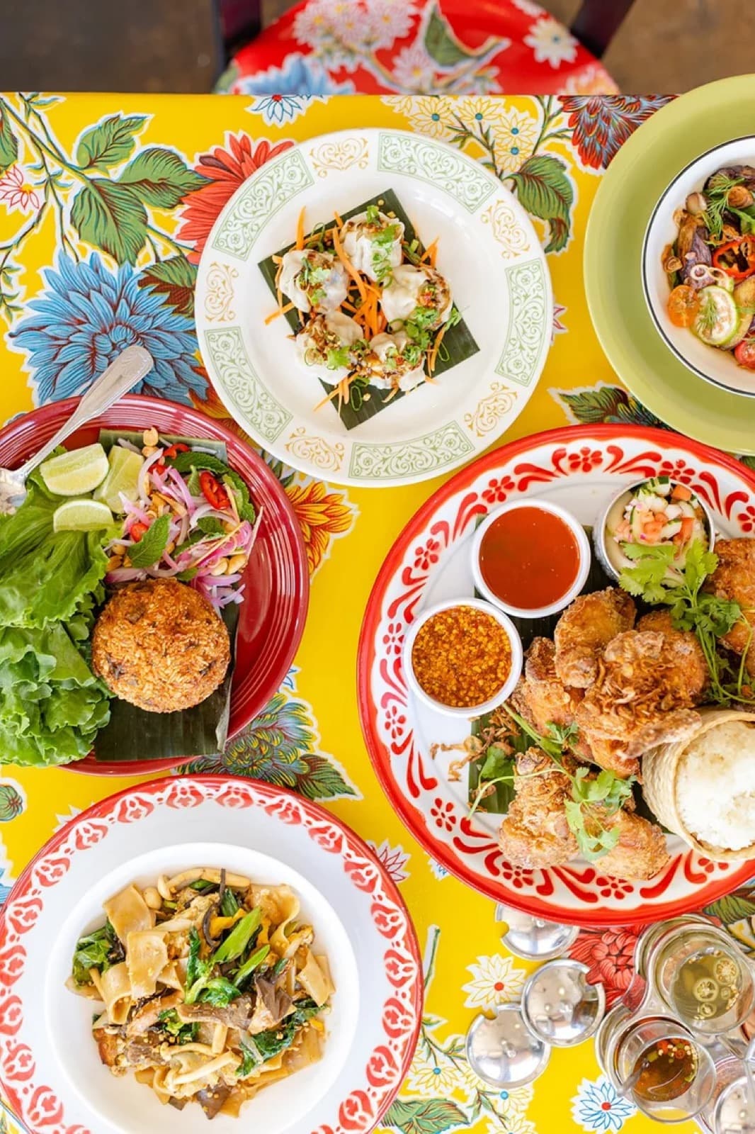 A colorful spread of Thai and Lao dishes at International Market, including larb, curry, and stir-fried noodles