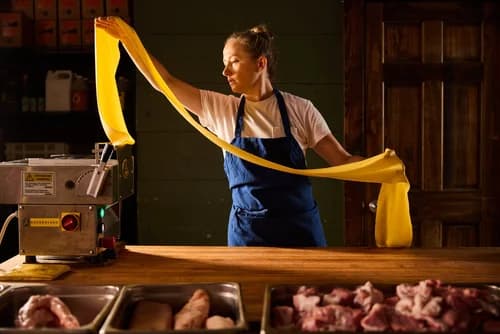 A cook hand-stretching fresh pasta dough over a butcher-block counter at Rolf and Daughters