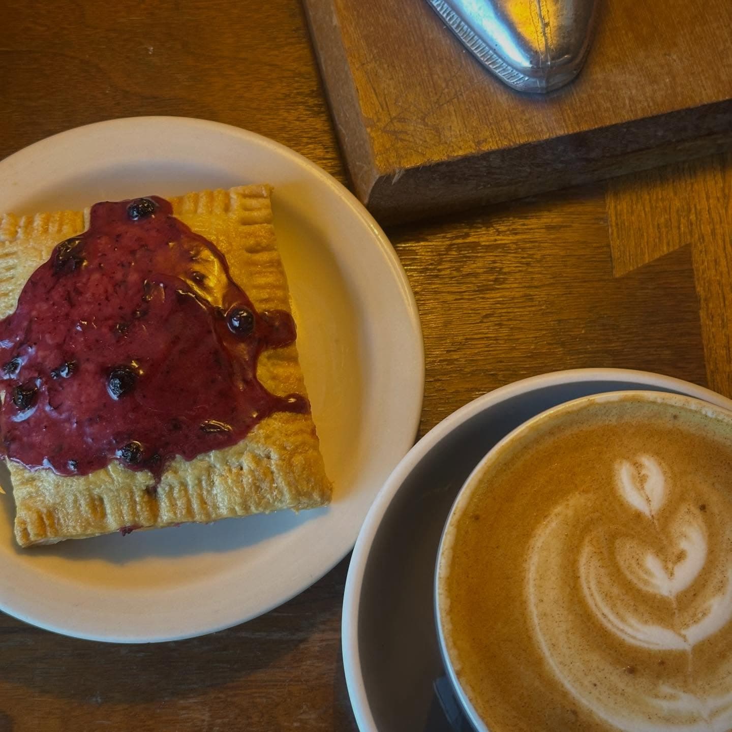 A blueberry hand pie and a latte with leaf-pattern foam art at Gray Owl Coffee