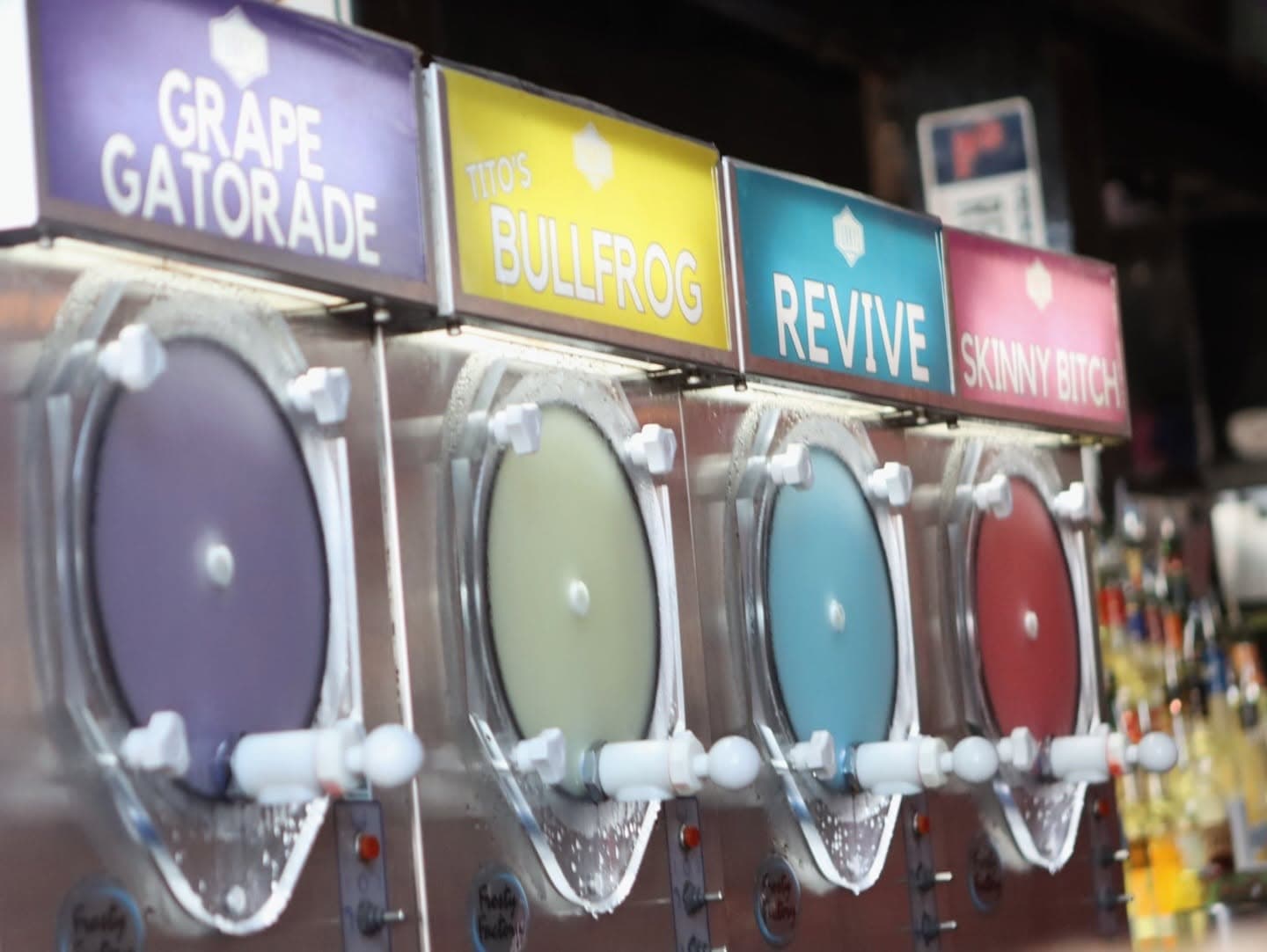 A row of frozen daiquiri machines at Funky's, flavors including Tito's Bullfrog and Grape Gatorade