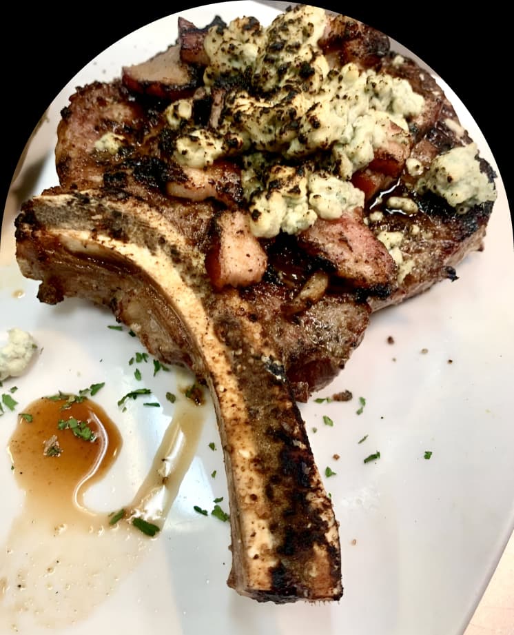 A bone-in ribeye topped with blue cheese crumbles and a bourbon reduction at The Oxford Grillehouse