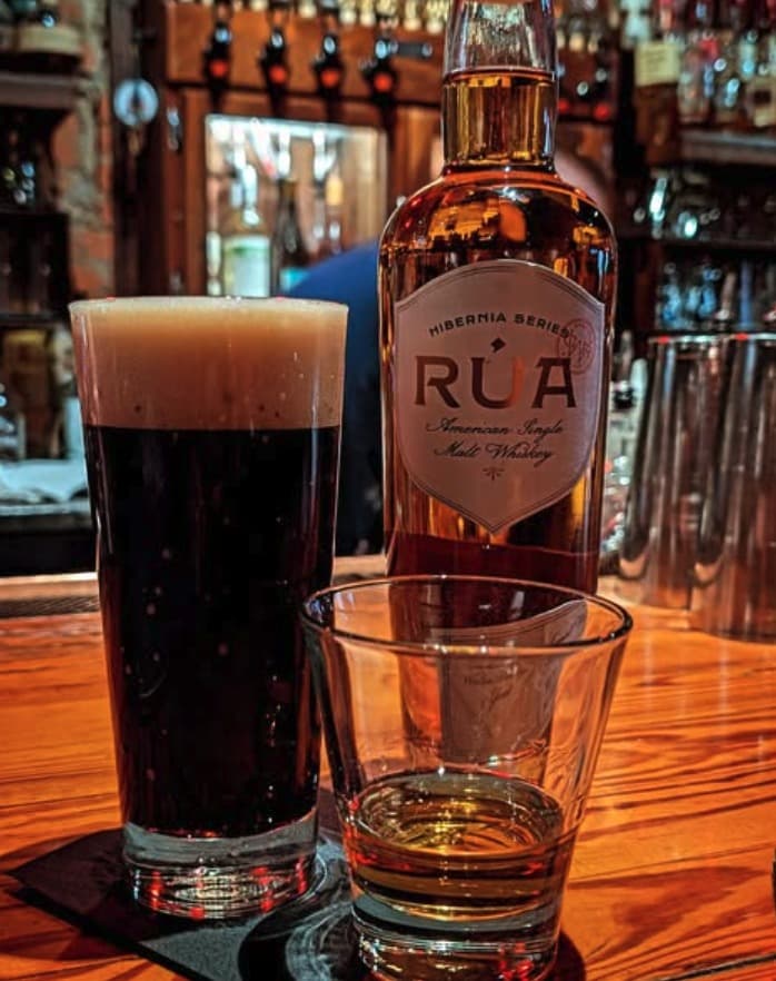 A pint of beer and an old fashioned next to a bottle of Rúa American Single Malt Whiskey on Foundation's bar