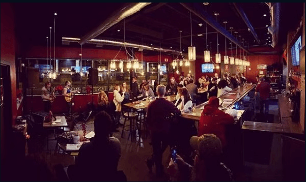 A packed crowd and live band performing inside Talking Cursive Brewing Company's taproom