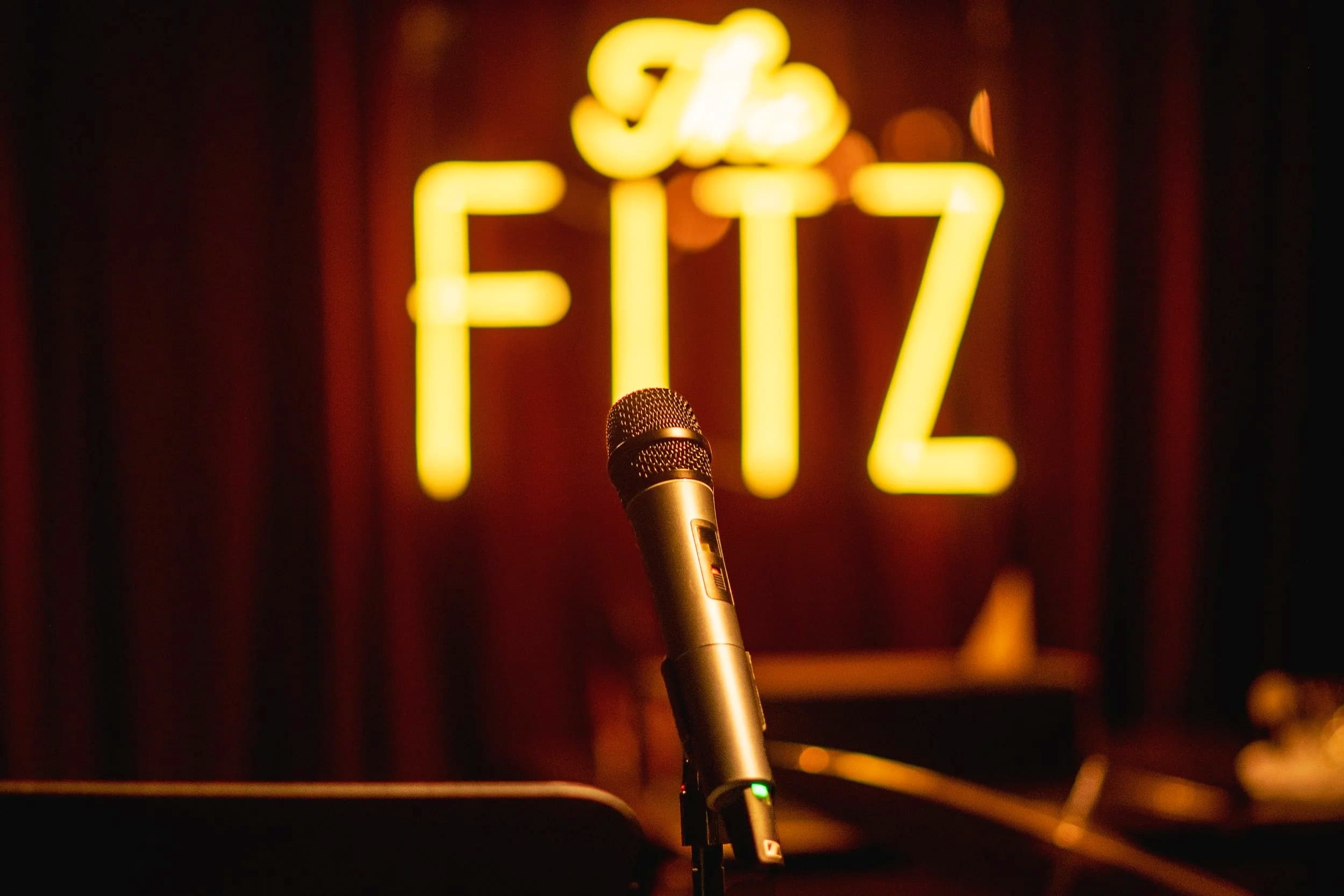 A microphone on stage in front of The Fitz's glowing neon sign